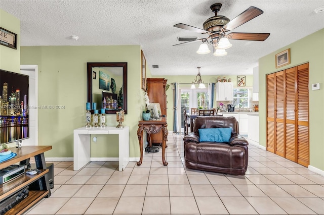 living room featuring ceiling fan, light tile patterned floors, and a textured ceiling