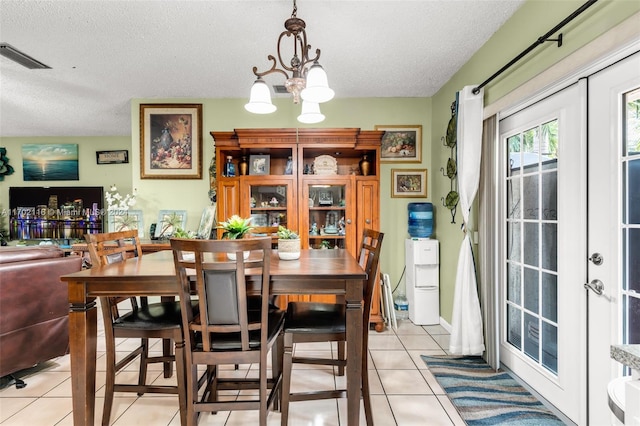 dining space featuring french doors, a textured ceiling, and light tile patterned floors