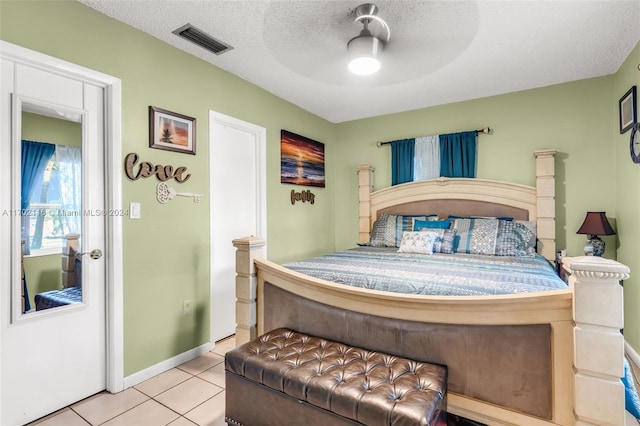 tiled bedroom with ceiling fan and a textured ceiling