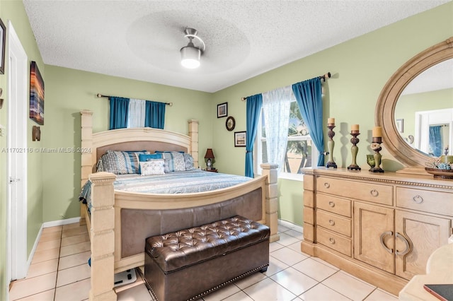 bedroom featuring ceiling fan, light tile patterned floors, and a textured ceiling