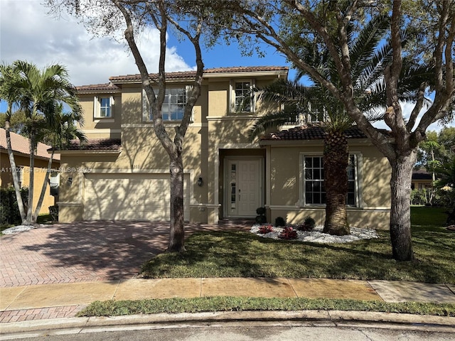 view of front of property with a garage, a tiled roof, decorative driveway, and stucco siding