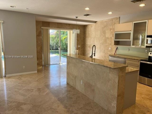 kitchen with stainless steel appliances, sink, hanging light fixtures, a kitchen island with sink, and light stone counters