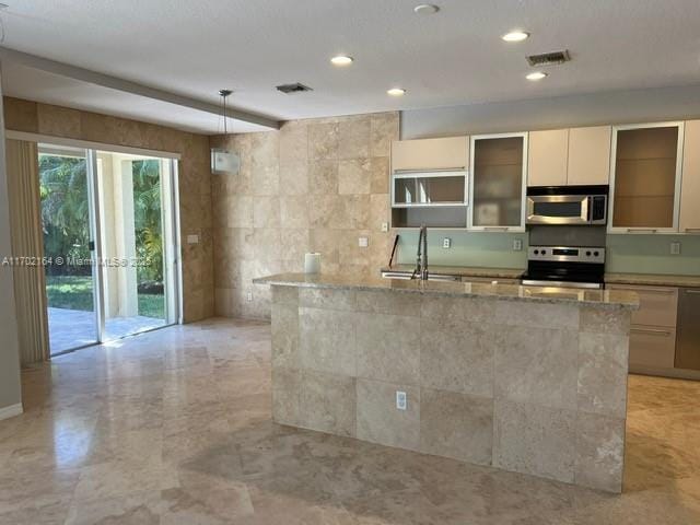 kitchen featuring white cabinetry, stove, hanging light fixtures, light stone counters, and sink