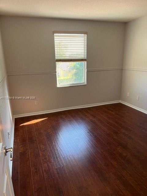 spare room with dark wood-type flooring