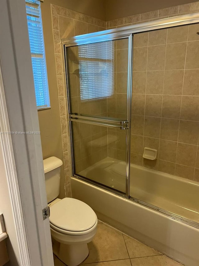 bathroom with shower / bath combination with glass door, toilet, and tile patterned flooring