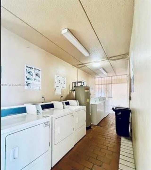 laundry room with washer and clothes dryer, water heater, and a textured ceiling