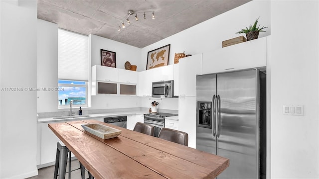 kitchen featuring a kitchen breakfast bar, white cabinetry, sink, and stainless steel appliances