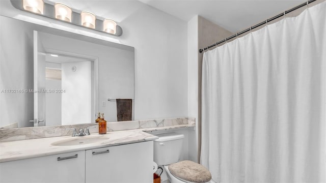 bathroom with walk in shower, vanity, and toilet