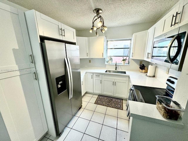 kitchen featuring sink, stainless steel appliances, light tile patterned floors, a textured ceiling, and white cabinets