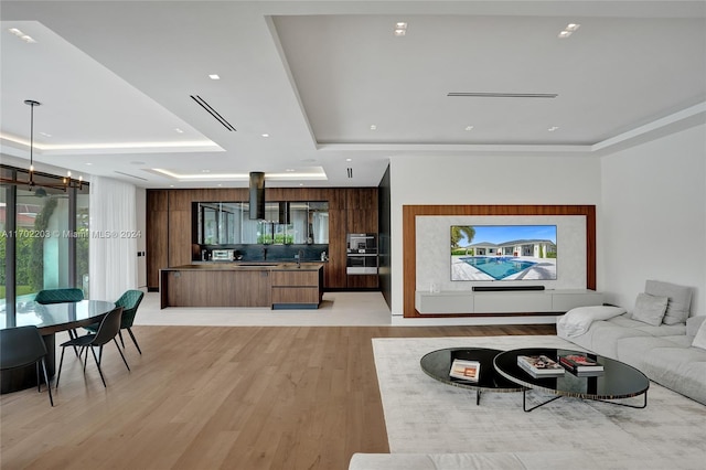 living room with a raised ceiling and light wood-type flooring