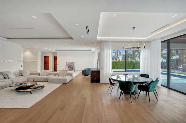 dining space featuring a chandelier, light hardwood / wood-style flooring, and a tray ceiling