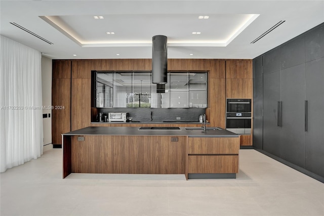 kitchen with black appliances, a spacious island, sink, and a tray ceiling