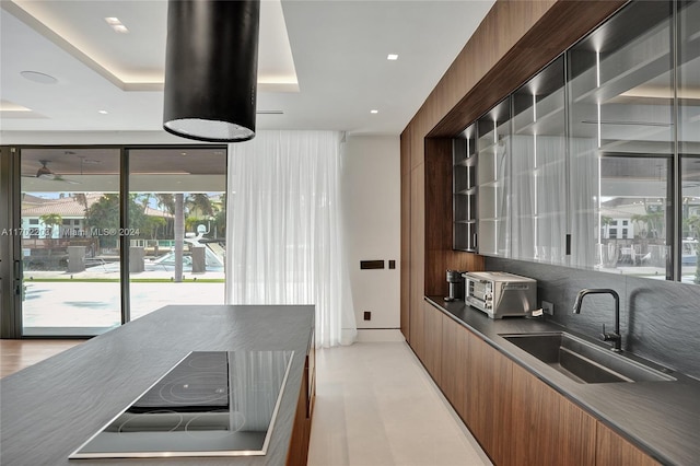 bar with light wood-type flooring, sink, and a tray ceiling