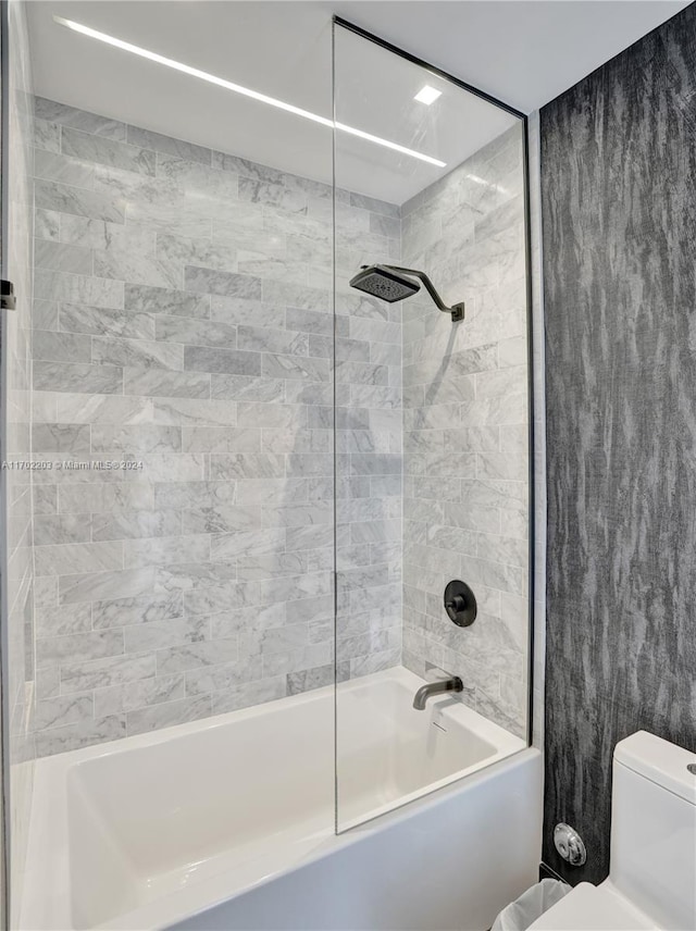 bathroom with tiled shower / bath combo and toilet