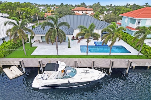 view of swimming pool featuring a boat dock, a water view, and a patio area