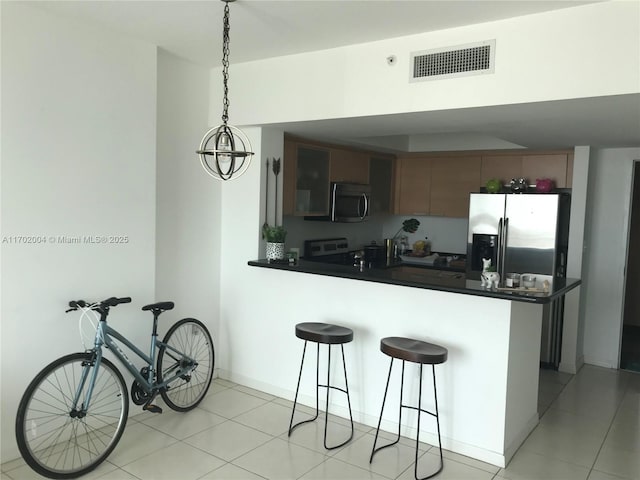 kitchen featuring kitchen peninsula, appliances with stainless steel finishes, a breakfast bar area, and light tile patterned flooring