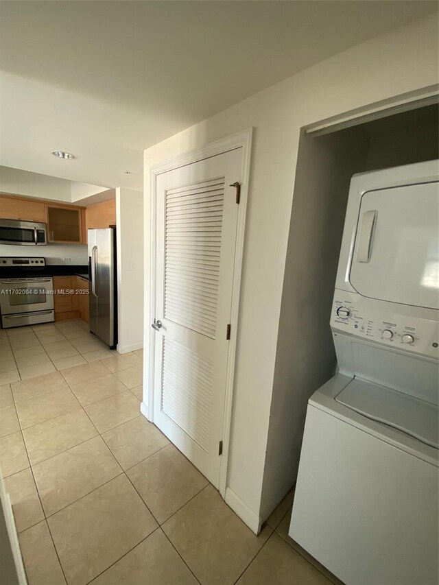 clothes washing area with light tile patterned floors and stacked washer / dryer