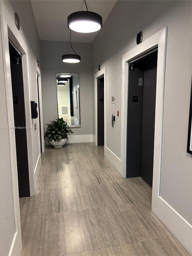 corridor with elevator and light hardwood / wood-style flooring