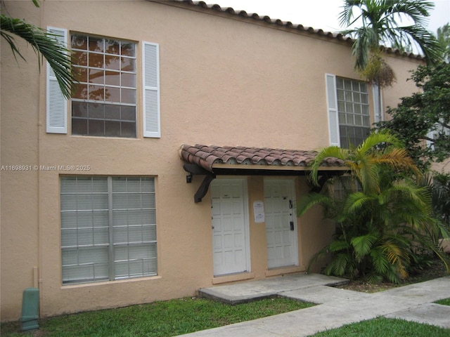 entrance to property featuring a tile roof and stucco siding