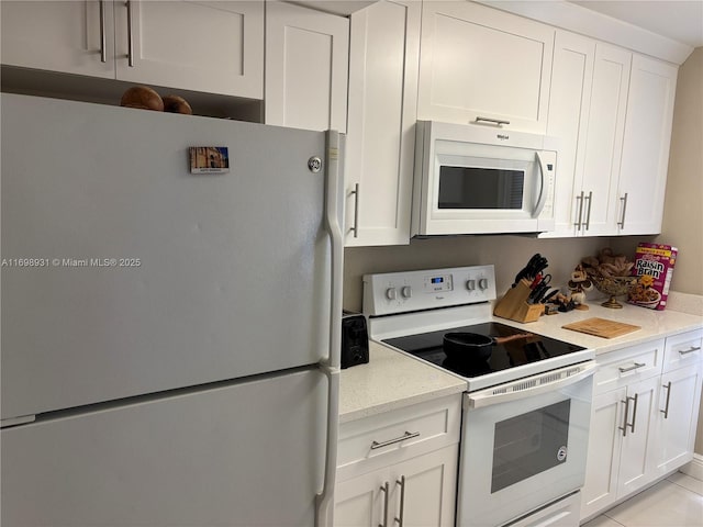 kitchen featuring light stone countertops, white appliances, and white cabinetry