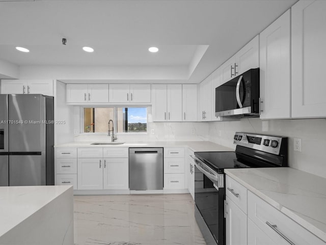 kitchen featuring stainless steel appliances, white cabinetry, a sink, and light stone countertops