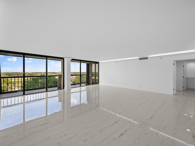 spare room with marble finish floor, a wall of windows, and visible vents