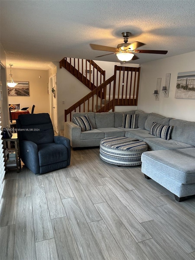 living room with a textured ceiling, hardwood / wood-style flooring, and ceiling fan