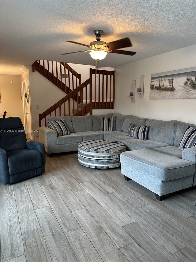 living room featuring hardwood / wood-style flooring, ceiling fan, and a textured ceiling