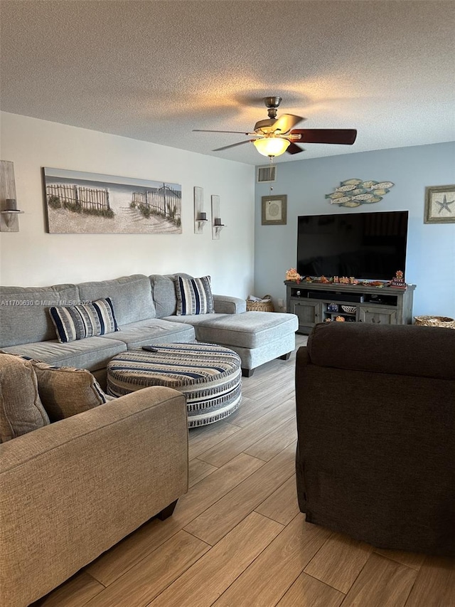 living room featuring ceiling fan, hardwood / wood-style floors, and a textured ceiling