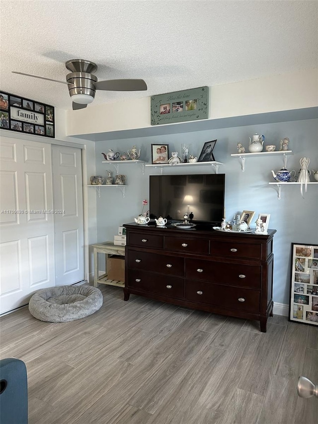 living room featuring a textured ceiling, light hardwood / wood-style flooring, and ceiling fan