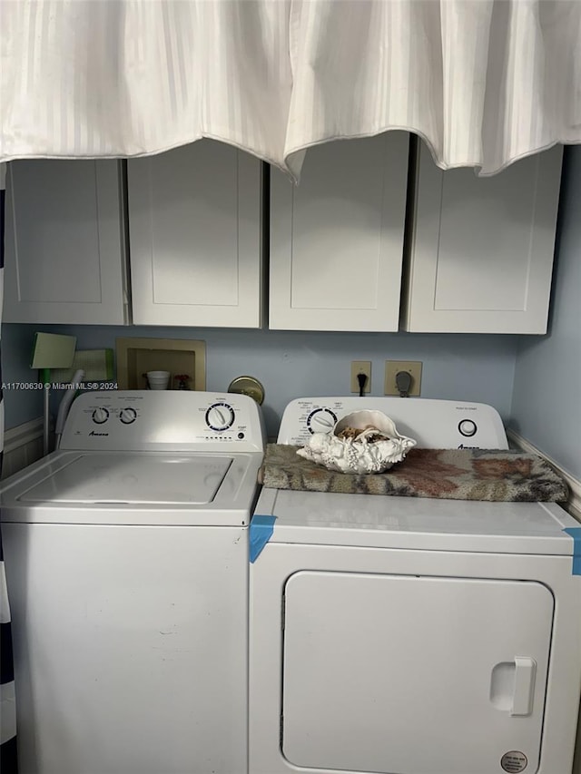 clothes washing area with cabinets and separate washer and dryer