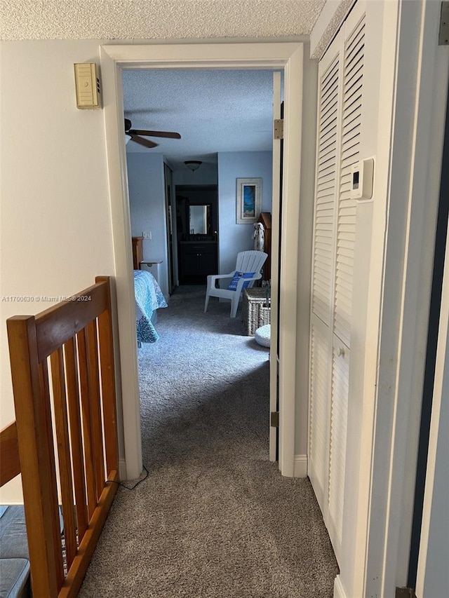 hallway featuring carpet flooring and a textured ceiling