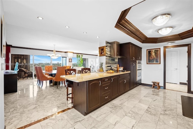 kitchen featuring hanging light fixtures, a kitchen bar, an inviting chandelier, crown molding, and dark brown cabinetry