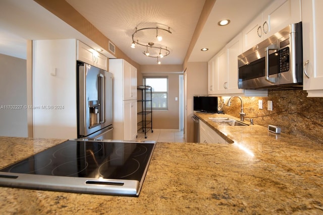 kitchen featuring backsplash, white cabinets, sink, light tile patterned floors, and appliances with stainless steel finishes