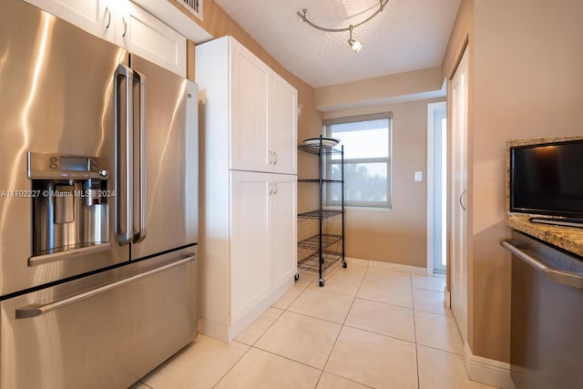 kitchen featuring white cabinets, light tile patterned flooring, stainless steel appliances, and stone counters