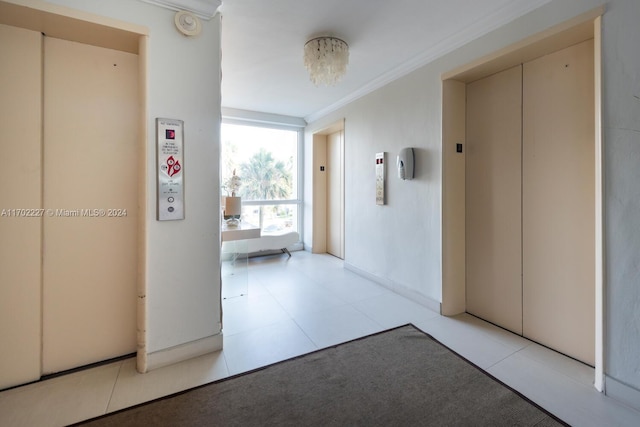 corridor with light tile patterned floors, elevator, an inviting chandelier, and ornamental molding