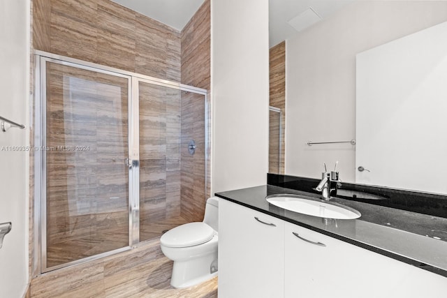 bathroom featuring vanity, an enclosed shower, and toilet