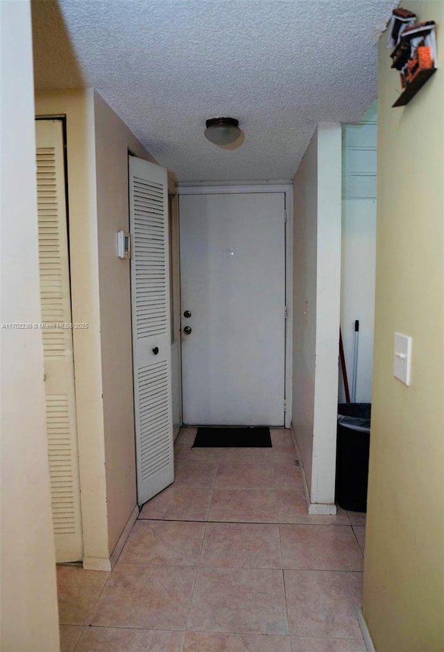 hallway featuring a textured ceiling and light tile patterned floors