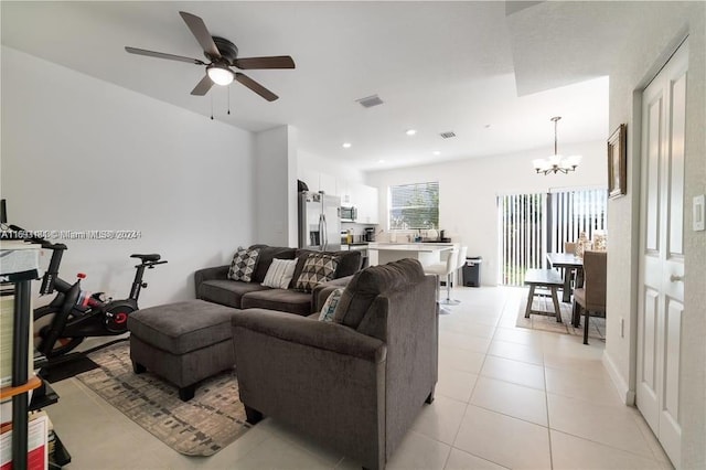 living room featuring ceiling fan with notable chandelier and light tile patterned floors