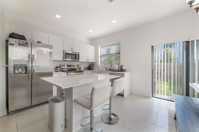 kitchen with stainless steel appliances, a kitchen island, plenty of natural light, and a breakfast bar area