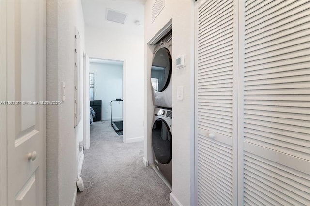 washroom featuring light carpet and stacked washer / dryer