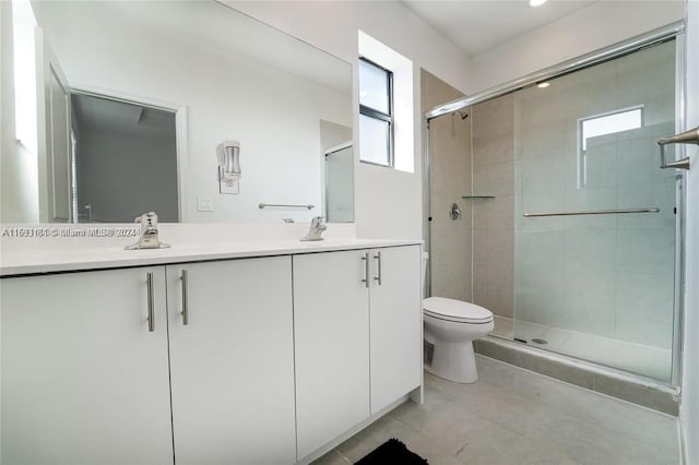 bathroom featuring tile patterned floors, vanity, toilet, and a shower with door