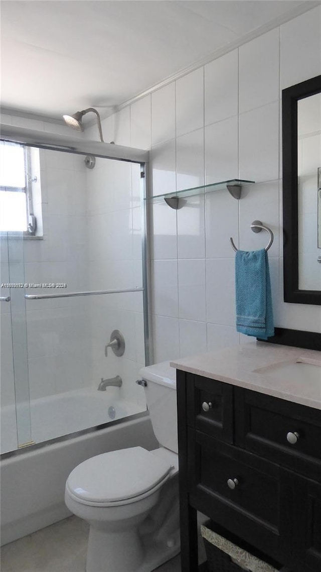 full bathroom featuring toilet, vanity, tile walls, and combined bath / shower with glass door