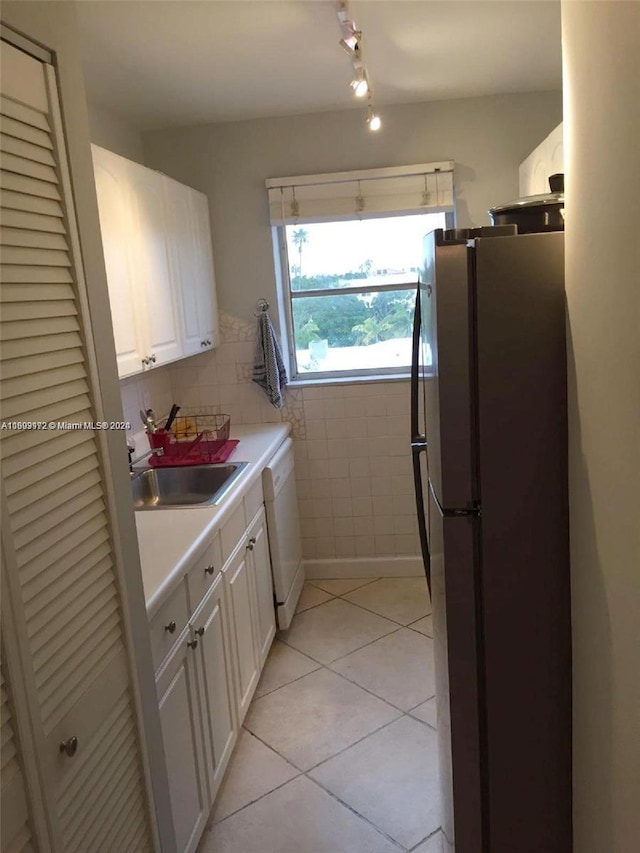 kitchen featuring dishwasher, white cabinets, sink, stainless steel fridge, and light tile patterned flooring