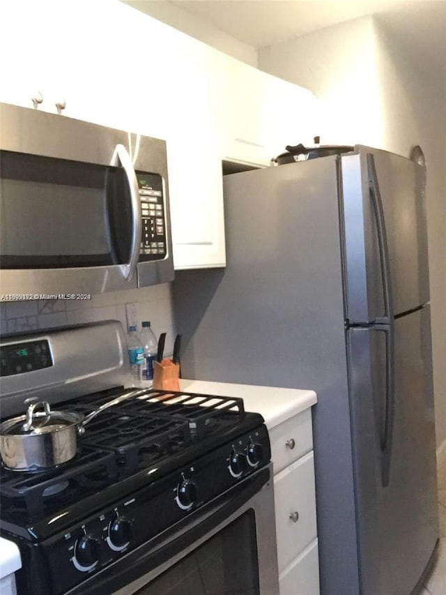 kitchen featuring decorative backsplash, white cabinetry, and appliances with stainless steel finishes