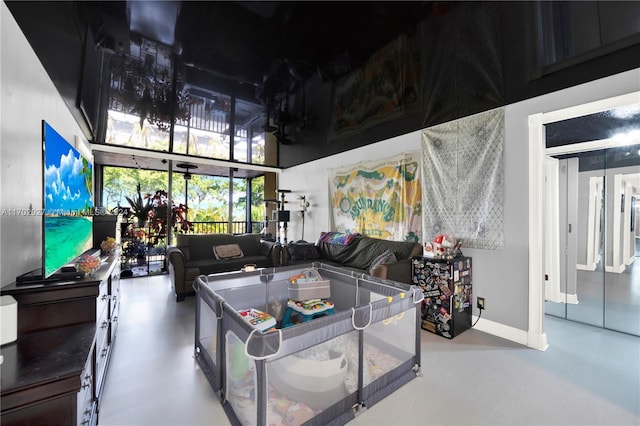 recreation room with a towering ceiling and concrete flooring