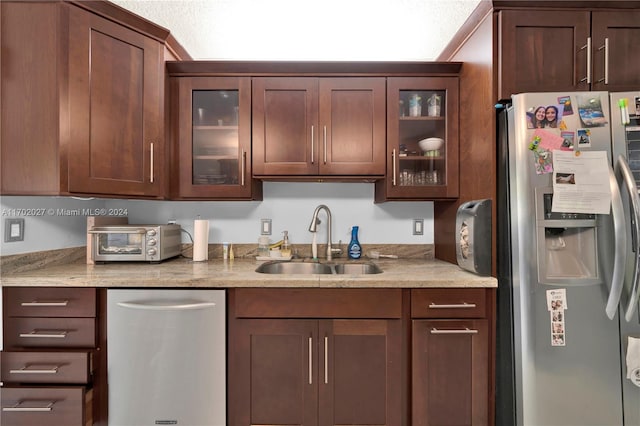 kitchen with light stone countertops, appliances with stainless steel finishes, and sink