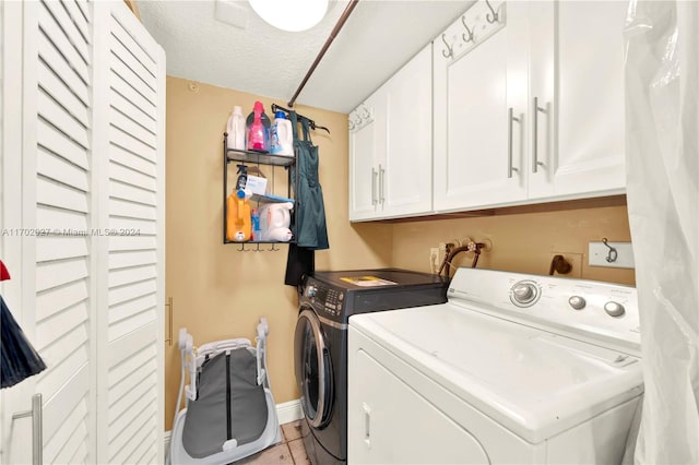 laundry room with washer and dryer, a textured ceiling, cabinets, and light tile patterned flooring