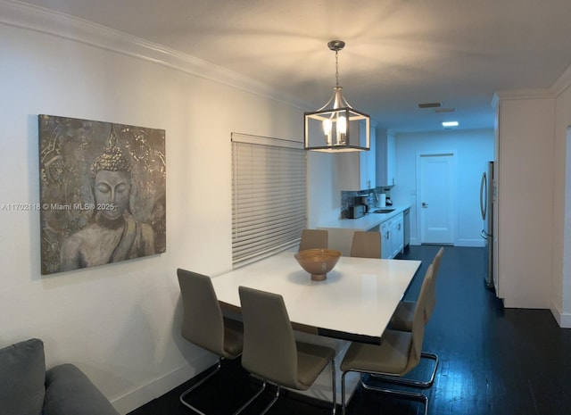 dining room with visible vents, baseboards, ornamental molding, and dark wood finished floors
