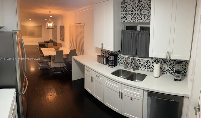 kitchen with dark wood-type flooring, light countertops, dishwashing machine, freestanding refrigerator, and a sink